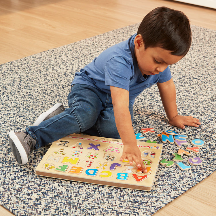 A kid playing with The Melissa & Doug Wooden Alphabet Sound Puzzle - Wooden Puzzle With Sound Effects (26 pcs)