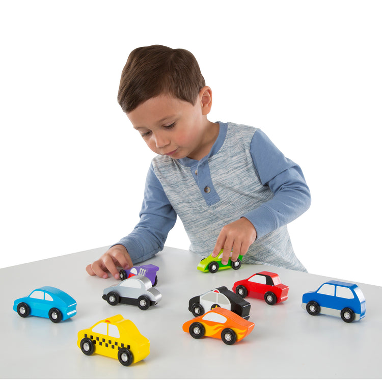 A child on white background with The Melissa & Doug Wooden Cars Vehicle Set in Wooden Tray - 9 Pieces