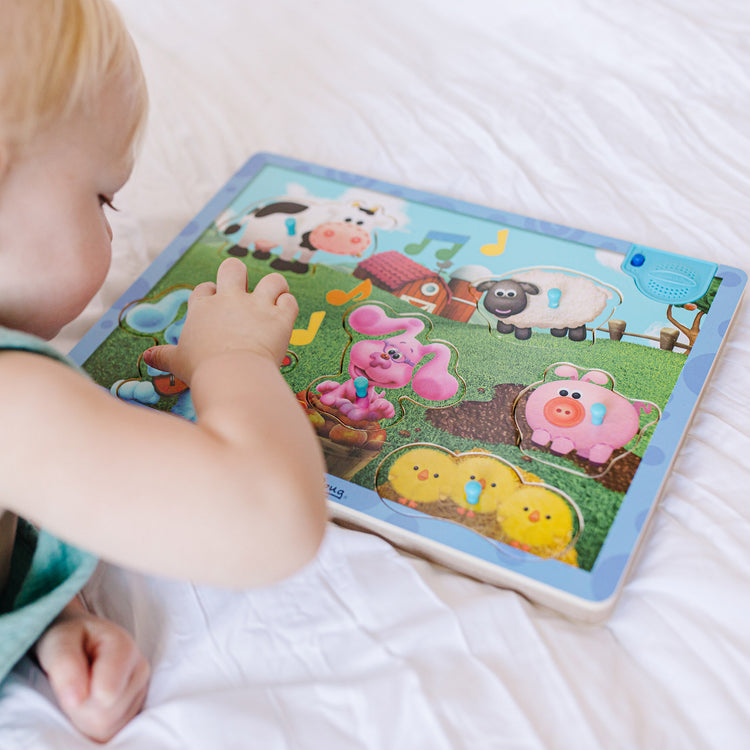 A kid playing with The Melissa & Doug Blue's Clues & You! Wooden Sound Puzzle - Musical Farm (6 Pieces)