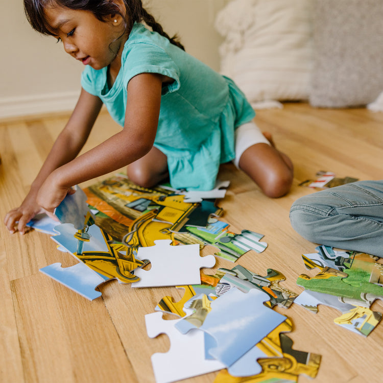 A kid playing with The Melissa & Doug Building Site Jumbo Jigsaw Floor Puzzle - 48 pcs