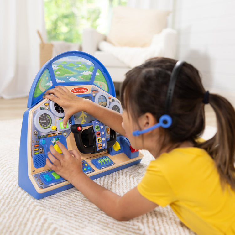 A kid playing with The Melissa & Doug Jet Pilot Interactive Dashboard Wooden Toy for Boys and Girls Ages 3+