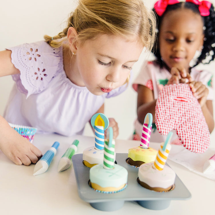 A kid playing with The Melissa & Doug Bake and Decorate Wooden Cupcake Play Food Set