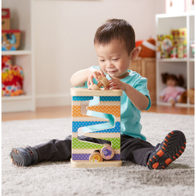 A kid playing with The Melissa & Doug First Play Wooden Safari Zig-Zag Tower With 4 Rolling Pieces