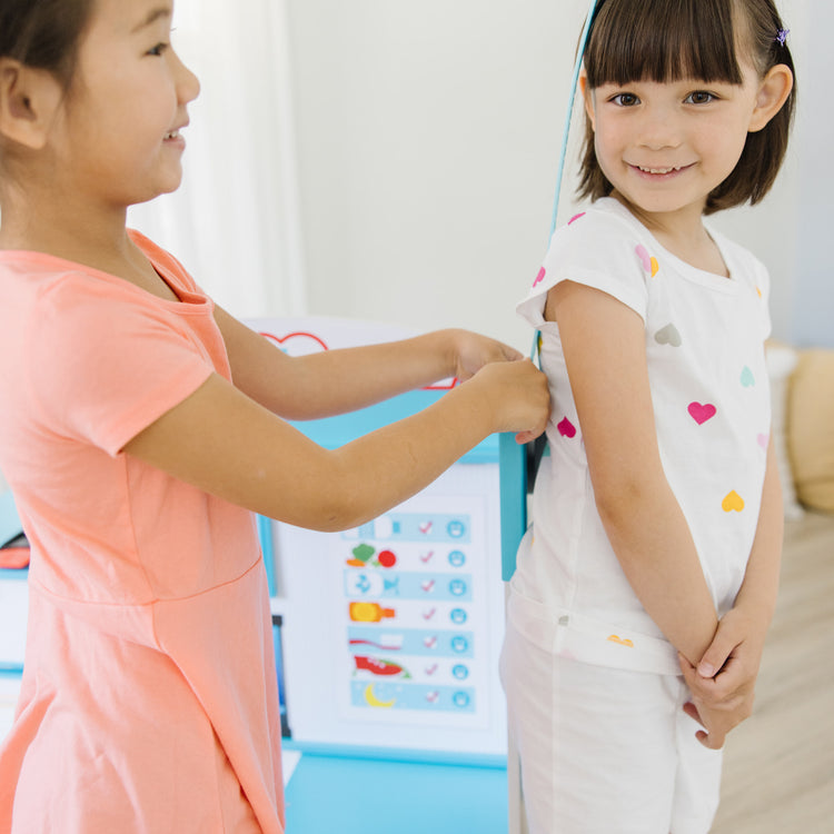 A kid playing with The Melissa & Doug Wooden Get Well Doctor Activity Center - Waiting Room, Exam Room, Check-In Area