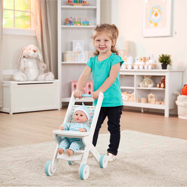 A kid playing with The Melissa & Doug Mine to Love Wooden Play Stroller for Dolls, Stuffed Animals - White (18”H x 8”W x 11”D Assembled)