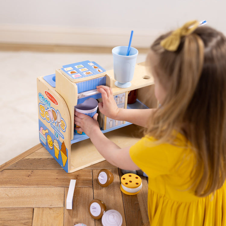 A kid playing with The Melissa & Doug Wooden Cool Scoops Ice Creamery Play Food Toy