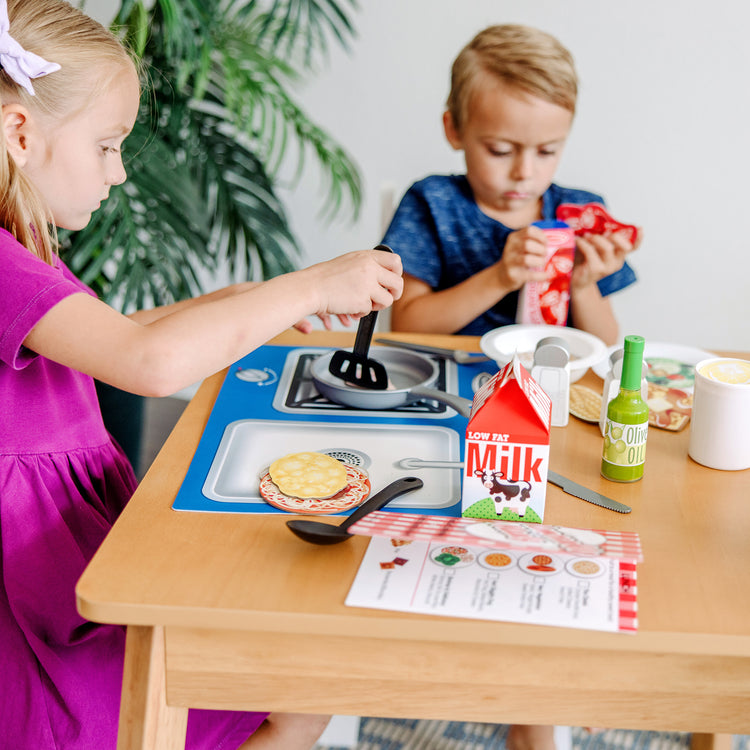 A kid playing with The Melissa & Doug Deluxe Kitchen Collection Cooking & Play Food Set – 58 Pieces