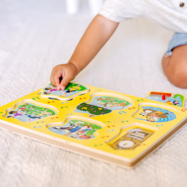 A kid playing with The Melissa & Doug Nursery Rhymes 1 Sound Puzzle - 6 PIeces