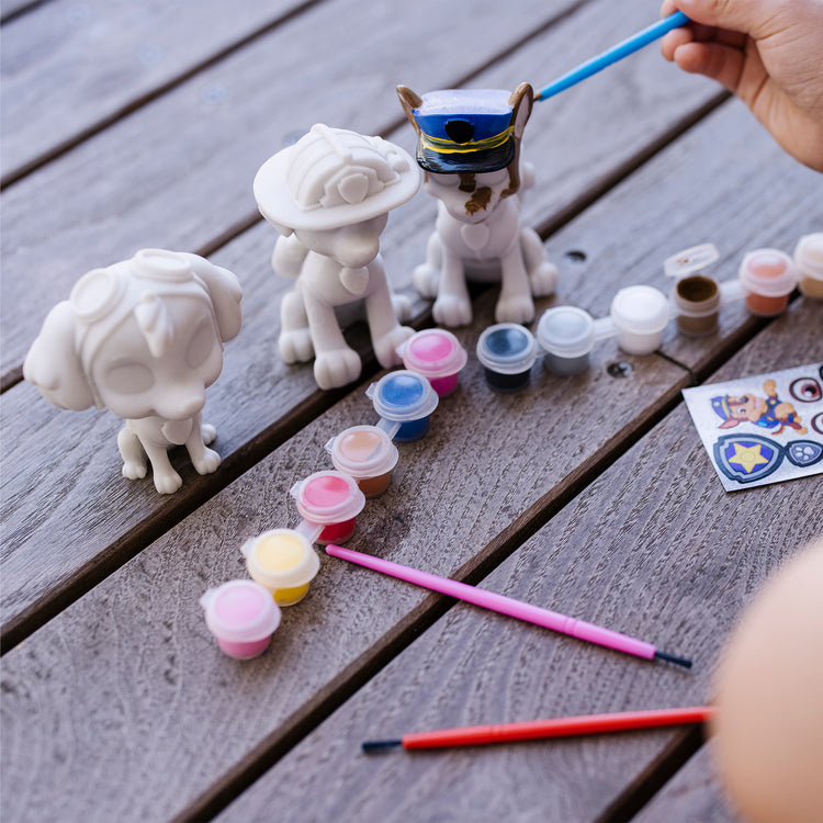 A kid playing with The Melissa & Doug PAW Patrol Craft Kit - 3 Decorate Your Own Pup Figurines