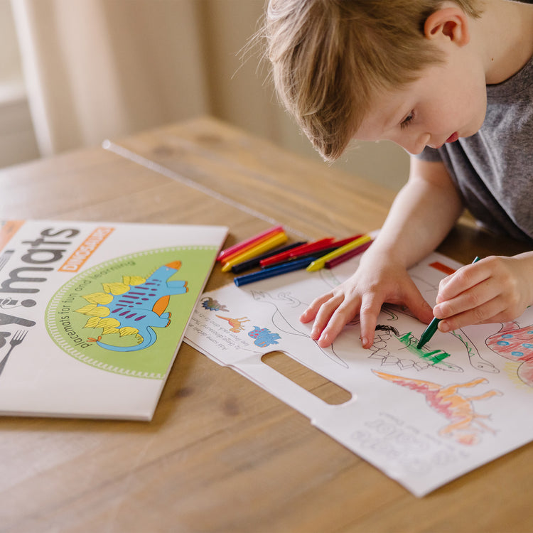 A kid playing with The Melissa & Doug Playmats Dinosaurs Take-Along Paper Coloring And Learning Activity Pads (24 Pages)