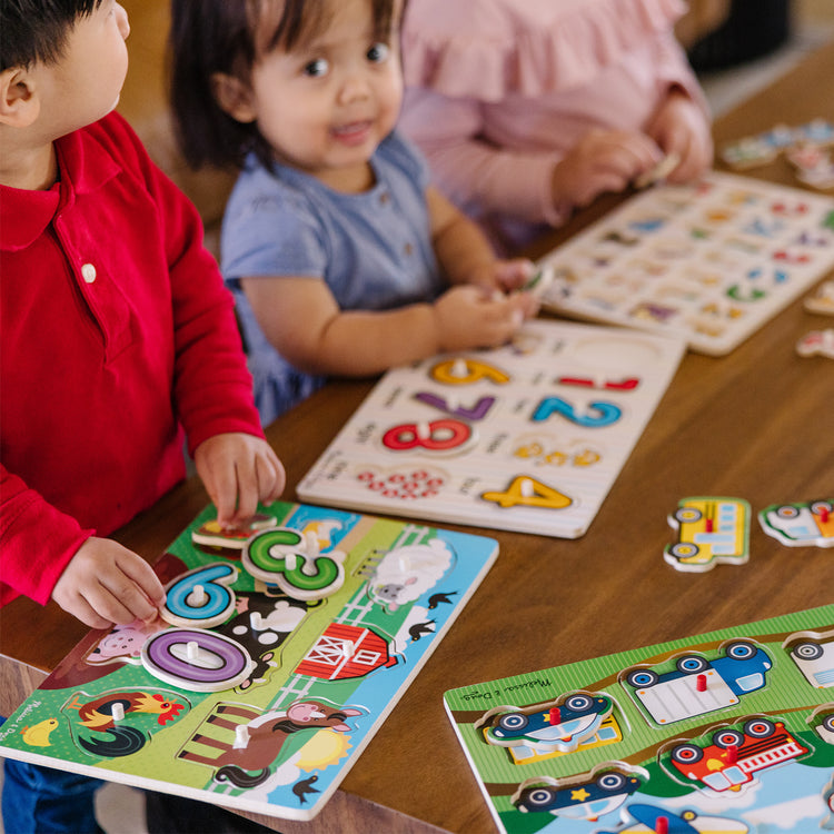 A kid playing with The Melissa & Doug Wooden Peg Puzzle 6-Pack – Numbers, Letters, 3 Animals, Vehicles