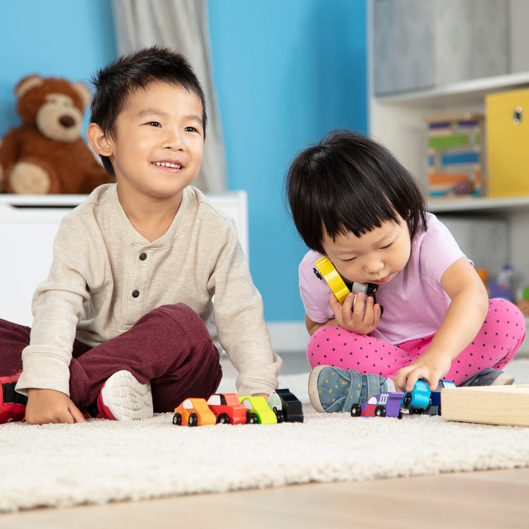 A kid playing with The Melissa & Doug Wooden Cars Vehicle Set in Wooden Tray - 9 Pieces