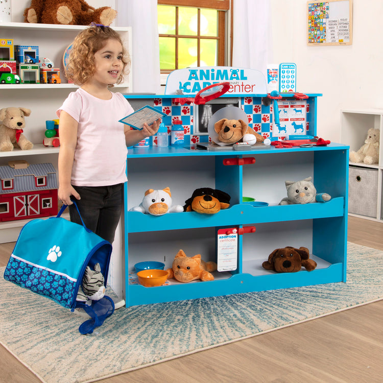 A kid playing with The Melissa & Doug Animal Care Veterinarian and Groomer Wooden Activity Center for Plush Stuffed Pets (Not Included)