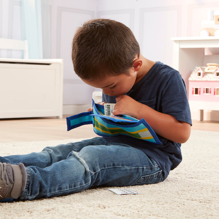 A kid playing with The Melissa & Doug Pretend-to-Spend Toy Wallet With Play Money and Cards (45 pcs), Blue