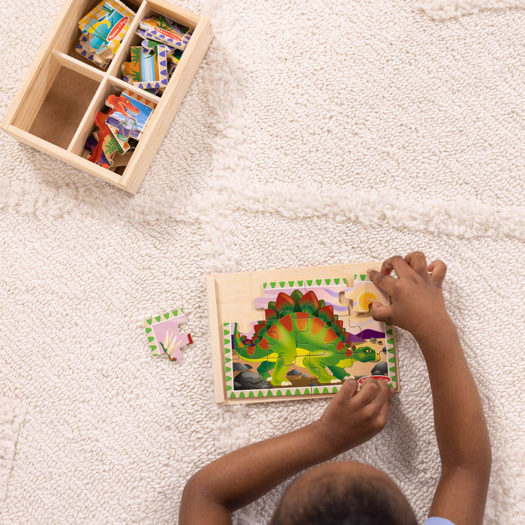 A kid playing with The Melissa & Doug Dinosaurs 4-in-1 Wooden Jigsaw Puzzles in a Storage Box (48 pcs)