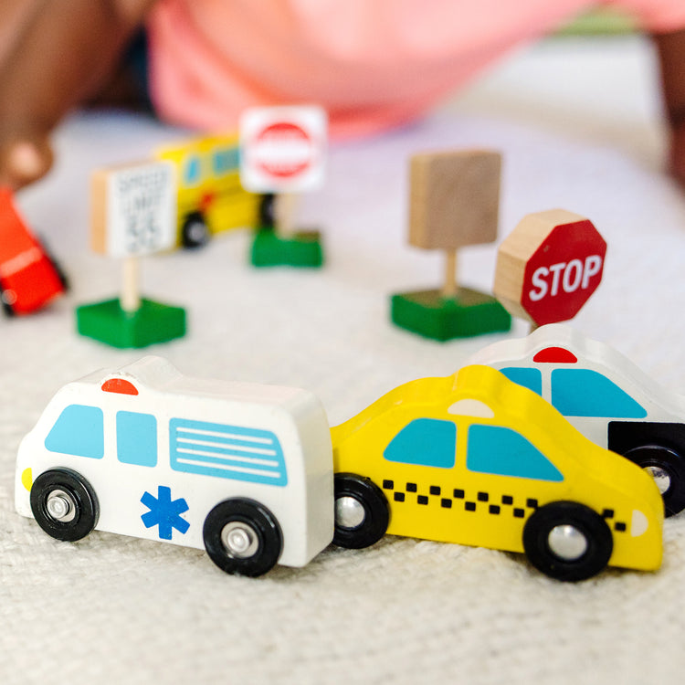 A kid playing with The Melissa & Doug Wooden Vehicles and Traffic Signs With 6 Cars and 9 Signs