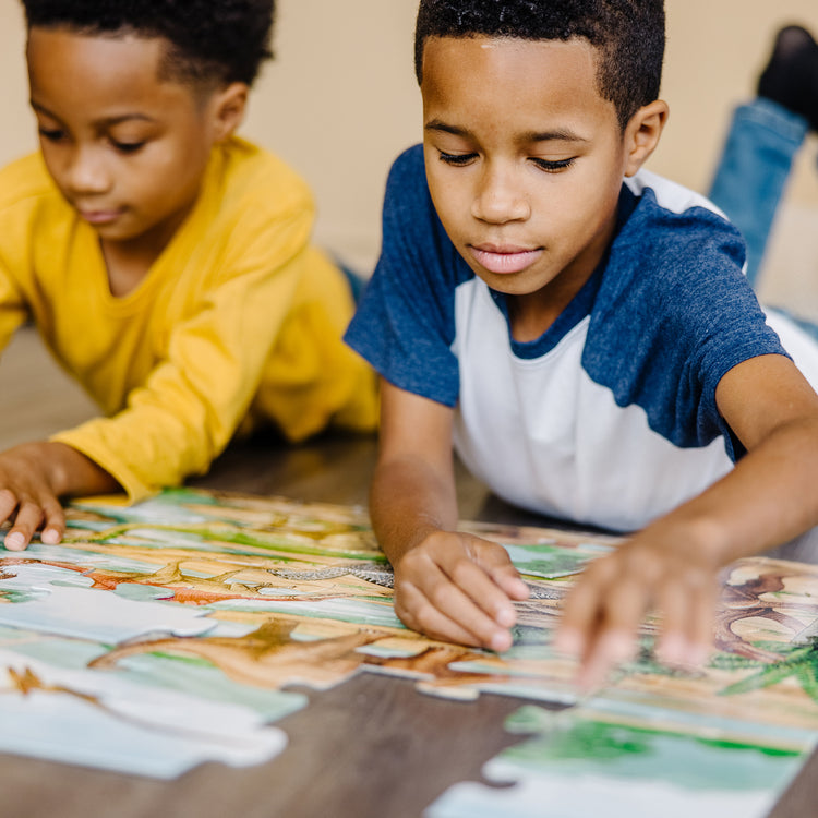 A kid playing with The Melissa & Doug Dinosaurs Floor Puzzle - 48 Pieces (2 Feet x 3 Feet Assembled)