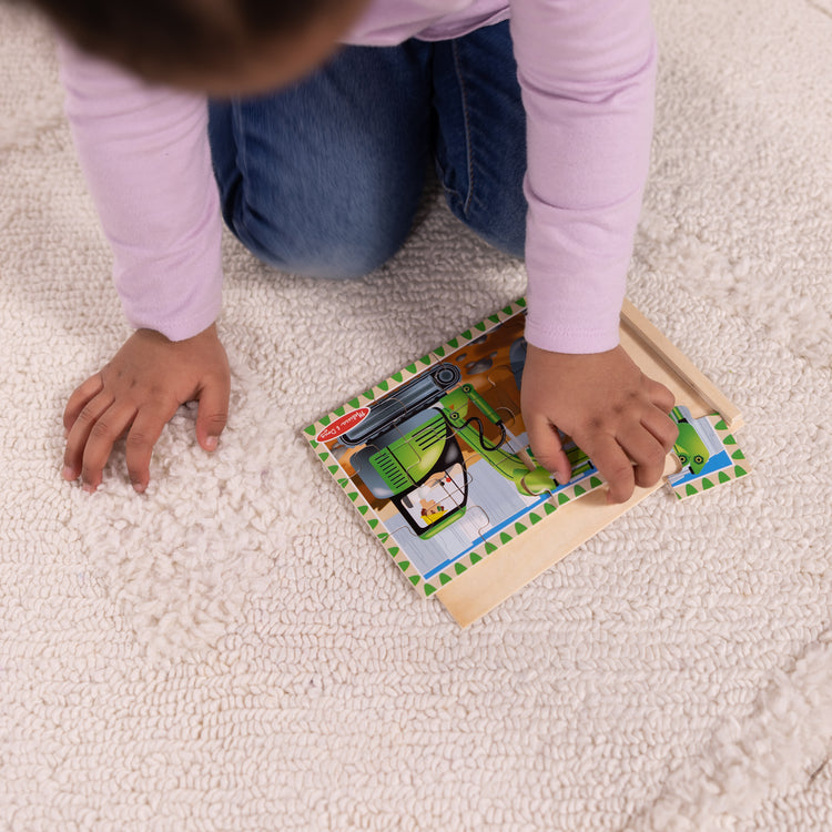 A kid playing with The Melissa & Doug Construction Vehicles 4-in-1 Wooden Jigsaw Puzzles in a Box (48 pcs)