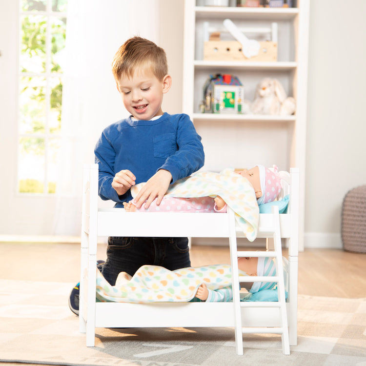 A kid playing with The Melissa & Doug Mine to Love Wooden Play Bunk Bed for Dolls, Stuffed Animals - White (2 Beds, 17.4”H x 9.1”W x 20.7”L Assembled and Stacked)