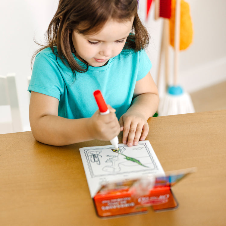 A kid playing with The Melissa & Doug On the Go ColorBlast! Travel Activity Book With No-Mess Marker - Dinosaur