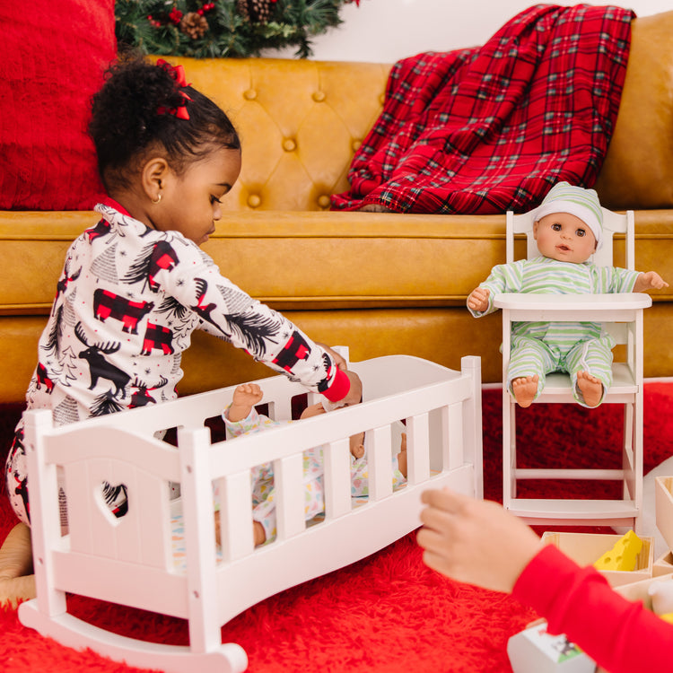 A kid playing with The Melissa & Doug Mine to Love Twins Sebastian & Sofia 15” Medium Skin-Tone Boy and Girl Baby Dolls with Rompers, Caps, Pacifiers