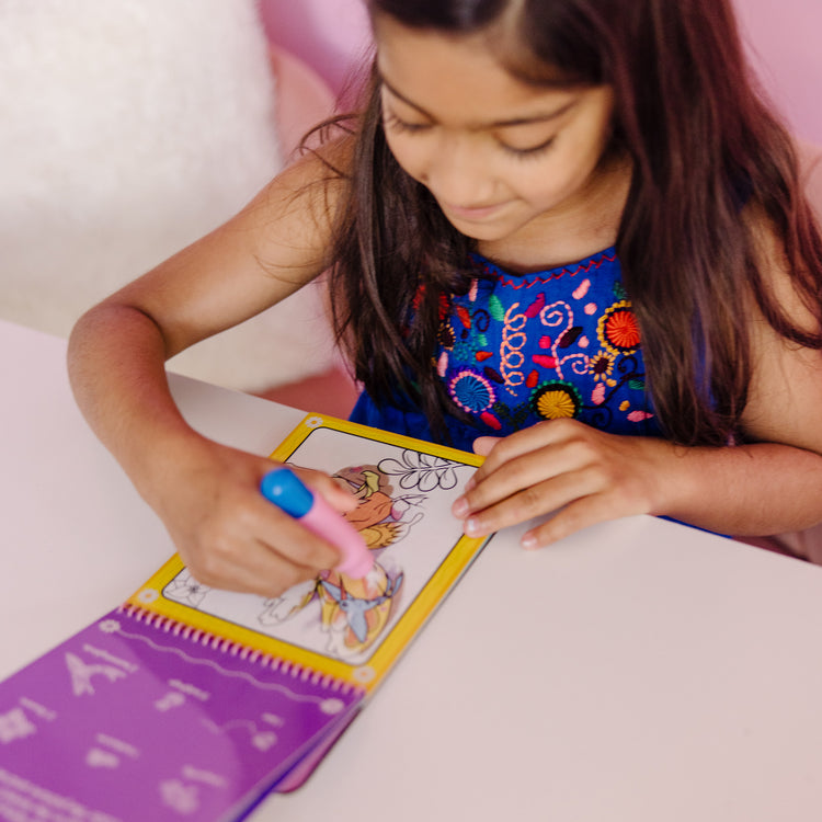 A kid playing with The Melissa & Doug On the Go Water Wow! Reusable Water-Reveal Activity Pad - Fairy Tale