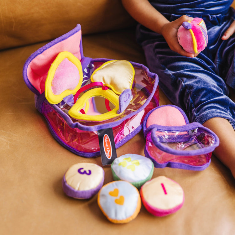 A kid playing with The Melissa & Doug Pretty Purse Fill and Spill Soft Play Set Toddler Toy