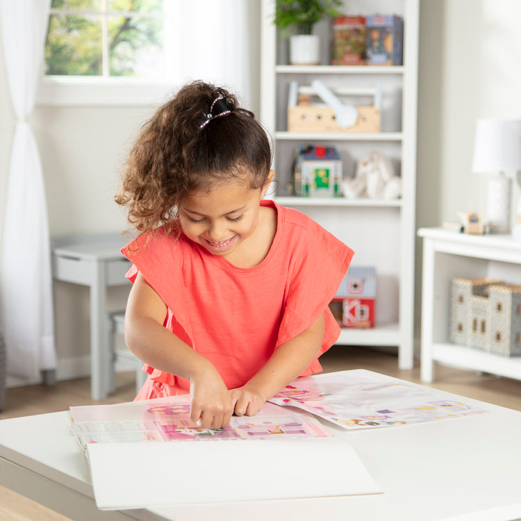 A kid playing with The Melissa & Doug Reusable Sticker Pad Set: Play House - 175+ Reusable Stickers