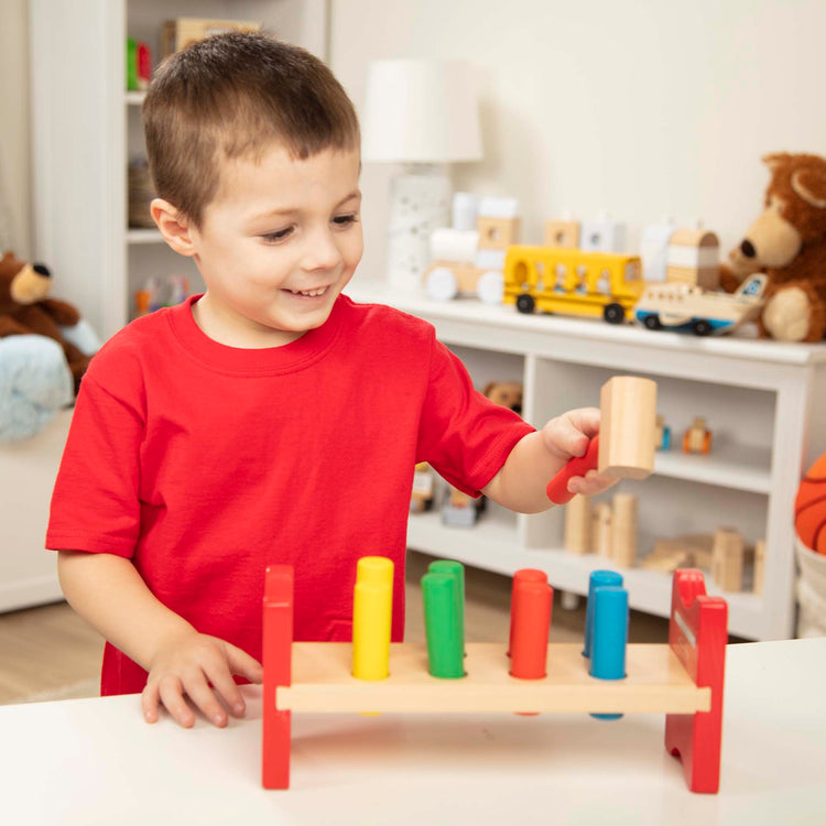 A kid playing with The Melissa & Doug Deluxe Wooden Pound-A-Peg Toy With Hammer