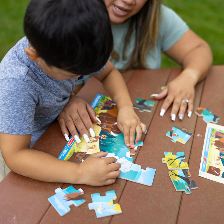 A kid playing with The Melissa & Doug Yellowstone National Park Wooden Jigsaw Puzzle – 24 Pieces, Animal and Plant ID Guide