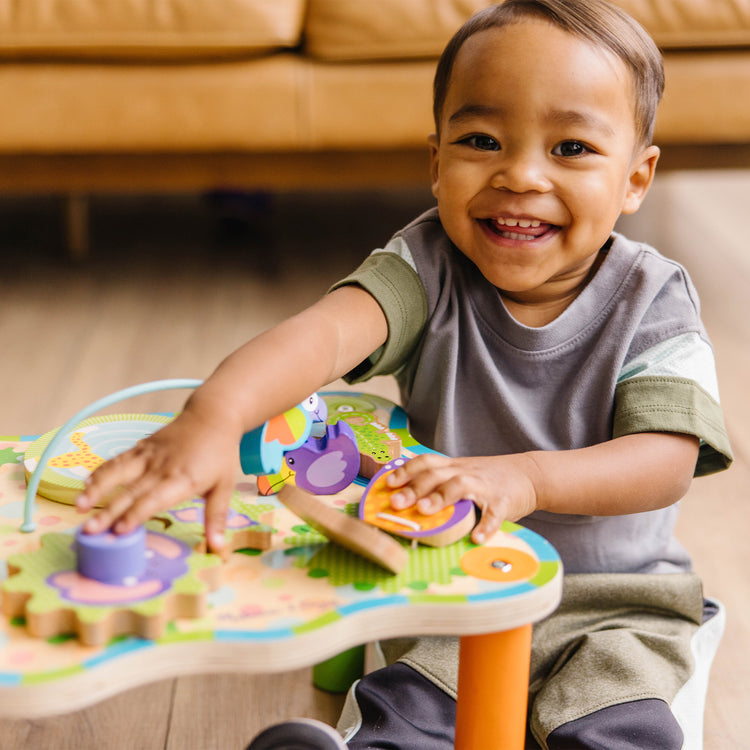 A kid playing with The Melissa & Doug First Play Children’s Jungle Wooden Activity Table for Toddlers