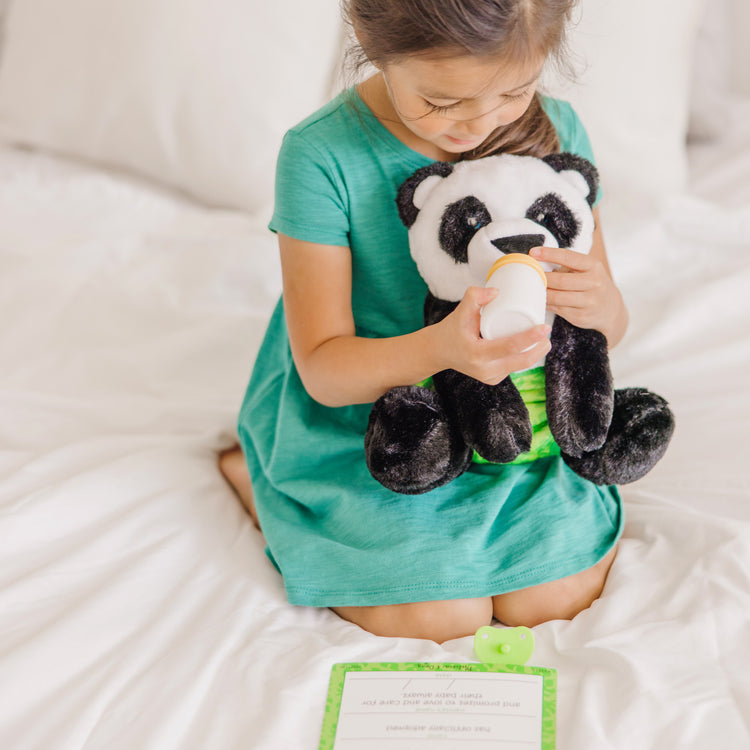 A kid playing with The Melissa & Doug 11-Inch Baby Panda Plush Stuffed Animal with Pacifier, Diaper, Baby Bottle