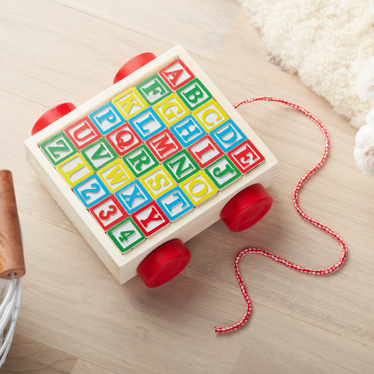 A playroom scene with The Melissa & Doug Classic ABC Wooden Block Cart Educational Toy With 30 1-Inch Solid Wood Blocks