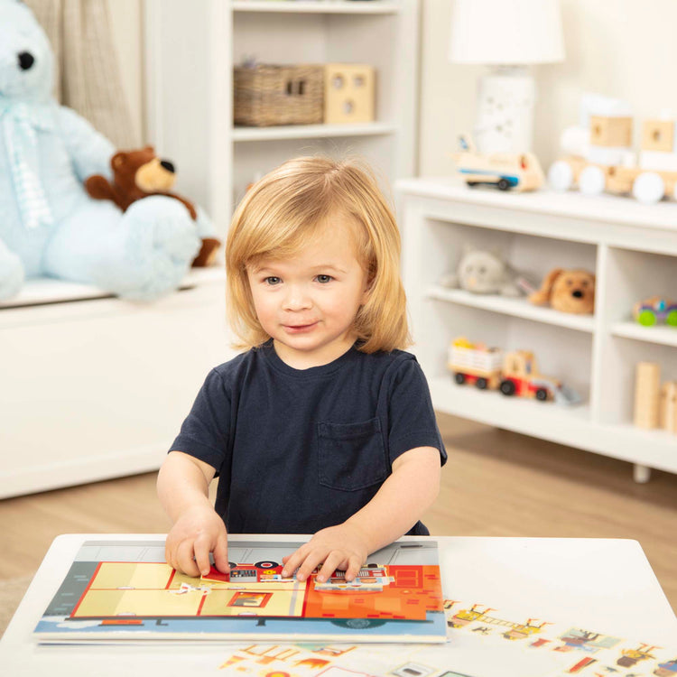 A kid playing with The Melissa & Doug Reusable Sticker Pad: My Town - 200+ Stickers and 5 Scenes