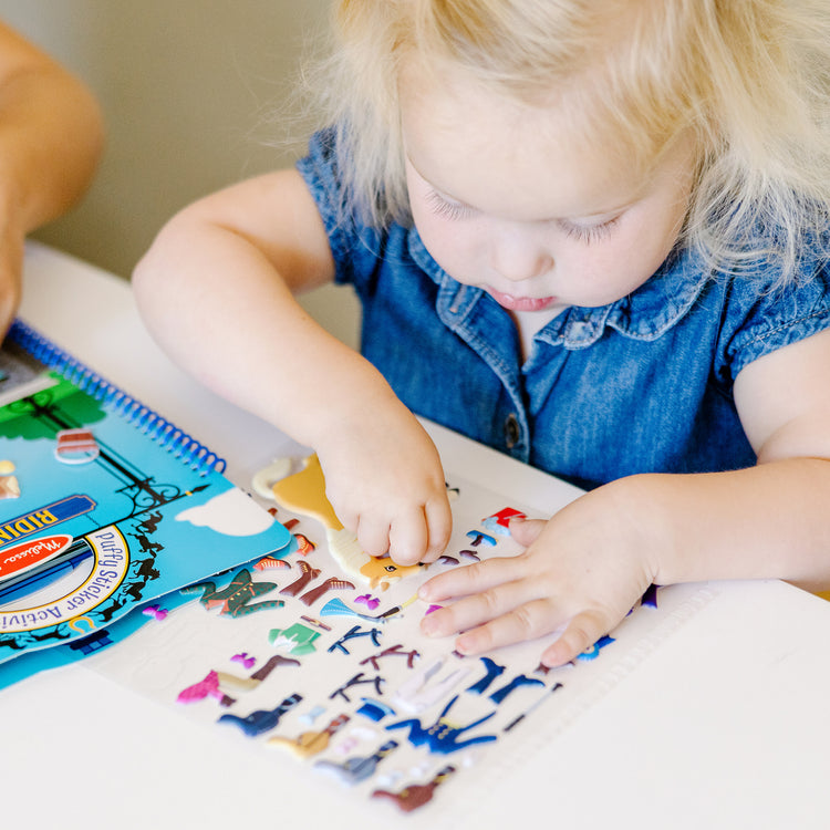 A kid playing with The Melissa & Doug Puffy Sticker Activity Book: Riding Club - 139 Reusable Stickers