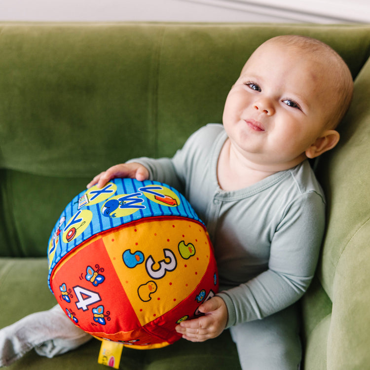 A kid playing with The Melissa & Doug K's Kids 2-in-1 Talking Ball Educational Toy - ABCs and Counting 1-10