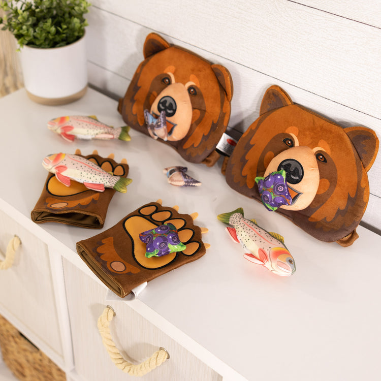 A playroom scene with The Melissa & Doug Yellowstone National Park Grizzly Bear Games and Pretend Play Set with Plush Bear Heads and Bear Paw Gloves