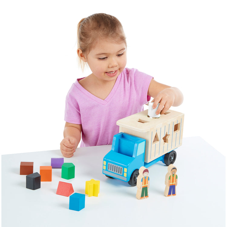 The loose pieces of The Melissa & Doug Shape-Sorting Wooden Dump Truck Toy With 9 Colorful Shapes and 2 Play Figures