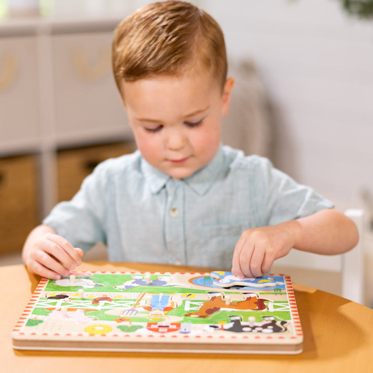 A kid playing with The Melissa & Doug Old MacDonald's Farm Sound Puzzle