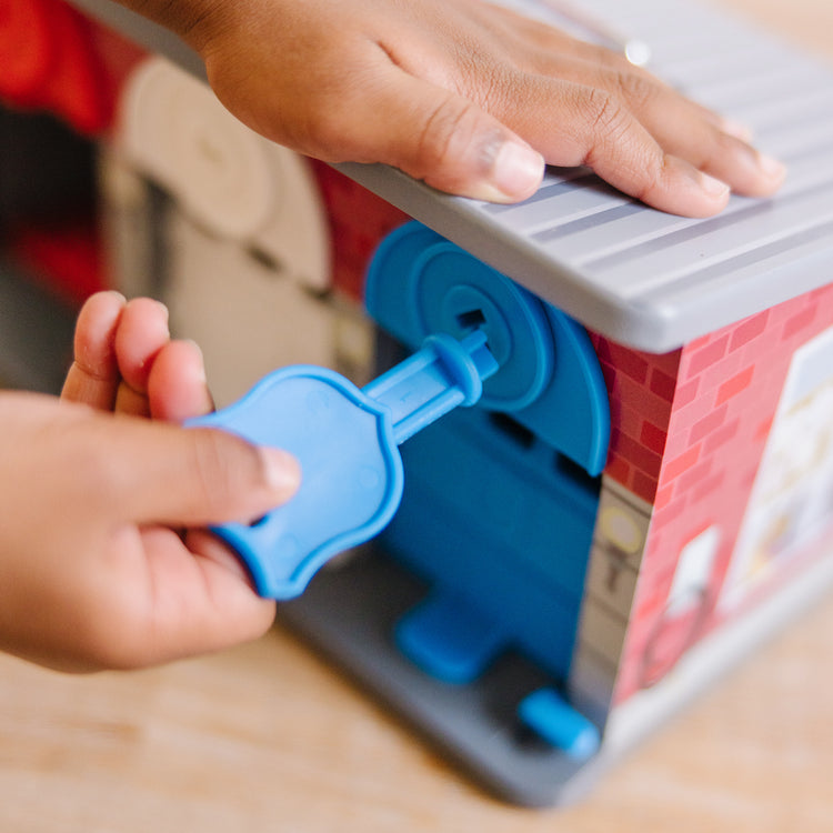 A kid playing with The Melissa & Doug Toy Keys and Cars Wooden Rescue Vehicles and Garage (7 pcs)