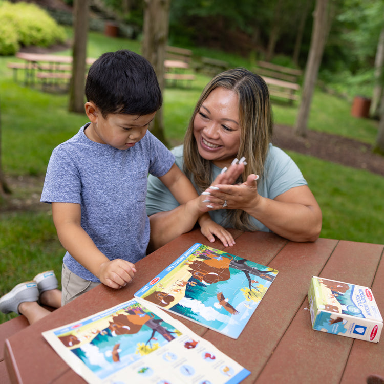 A kid playing with The Melissa & Doug Yellowstone National Park Wooden Jigsaw Puzzle – 24 Pieces, Animal and Plant ID Guide