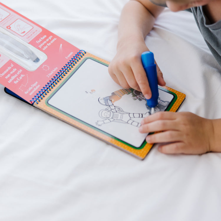 A kid playing with The Melissa & Doug On the Go Space Water Wow! Reusable Mess-Free Water-Reveal Activity Pad