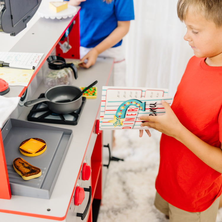 A kid playing with The Melissa & Doug Double-Sided Wooden Star Diner Restaurant Play Space