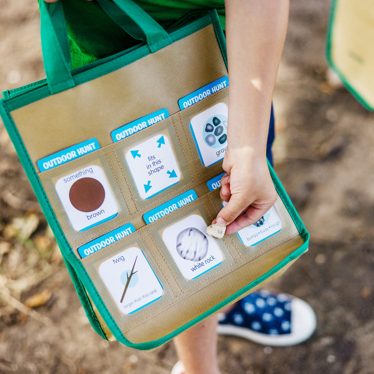 A kid playing with The Melissa & Doug Let’s Explore Indoor/Outdoor Scavenger Hunt Play Set – 80 Double-Sided Cards