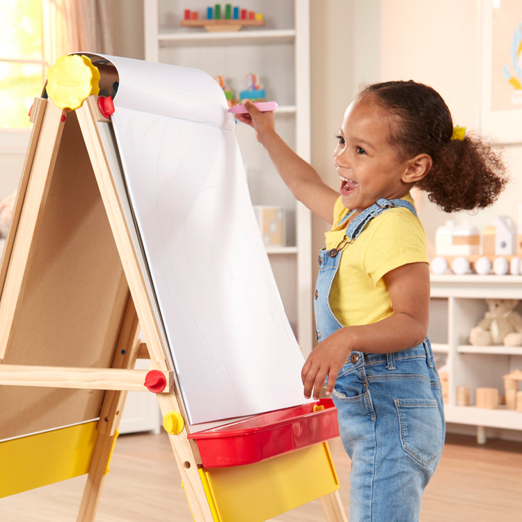 A kid playing with The Melissa & Doug Art Essentials Easel Pad (17 x 20 inches) With 50 Sheets of White Bond Paper