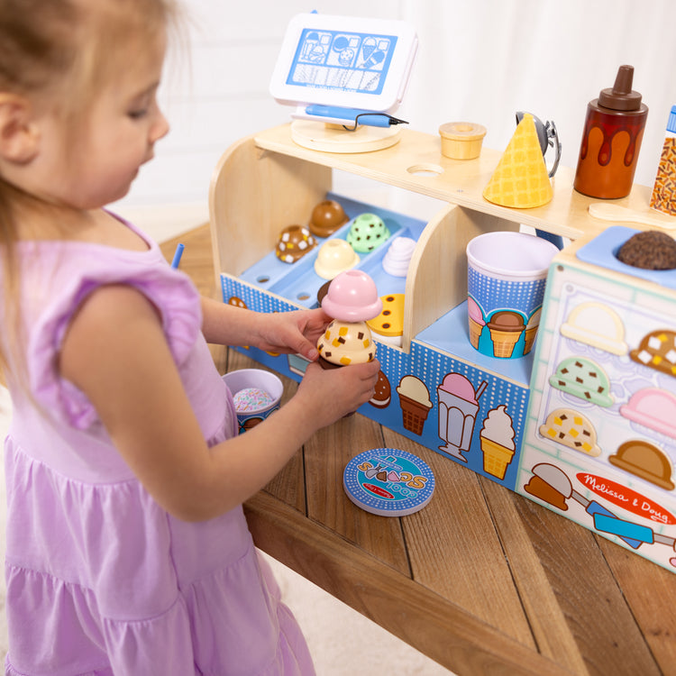 A kid playing with The Melissa & Doug Wooden Cool Scoops Ice Creamery Play Food Toy