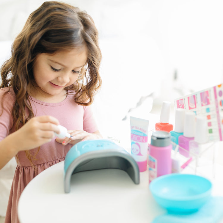 A kid playing with The Melissa & Doug Love Your Look Pretend Nail Care Play Set – 22 Pieces for Mess-Free Play Mani-Pedis (DOES NOT CONTAIN REAL COSMETICS)