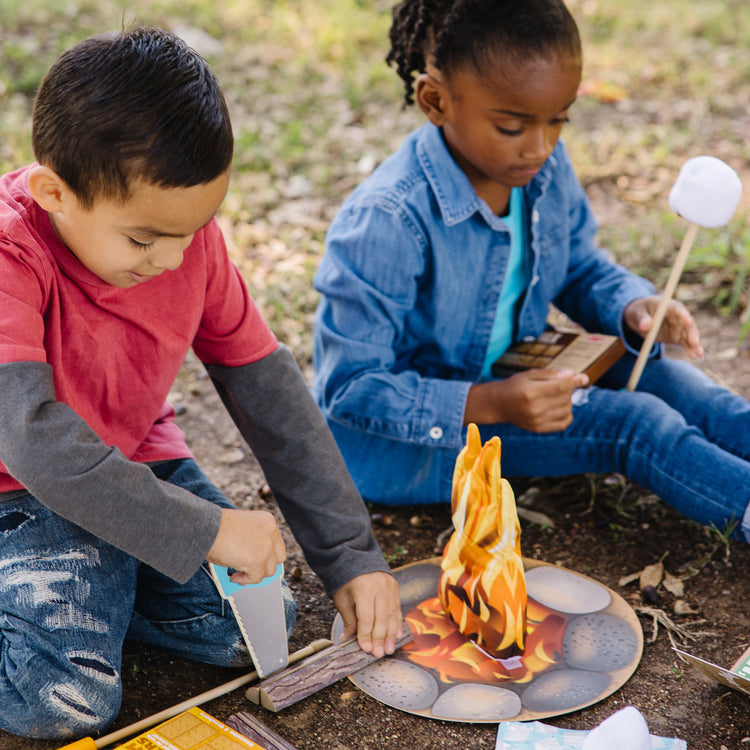 A kid playing with The Melissa & Doug Let's Explore Campfire S'Mores Play Set