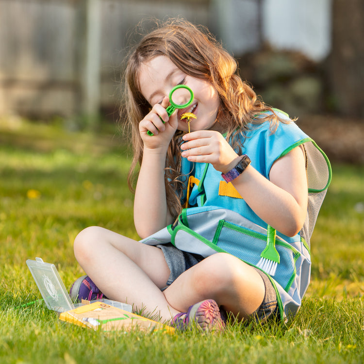 A kid playing with The Melissa & Doug Let’s Explore Naturalist Vest Play Set – 20 Pieces