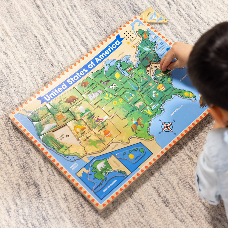 A kid playing with The Melissa & Doug USA Map Sound Puzzle - Wooden Puzzle With Sound Effects (40 pcs), Multicolor